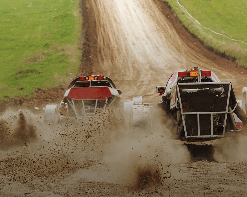 Off-road buggies racing on muddy track.